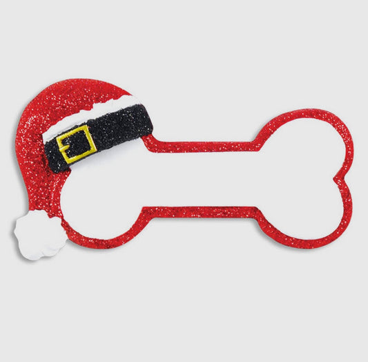 A white dog bone ornament trimmed in red with a red Santa hat