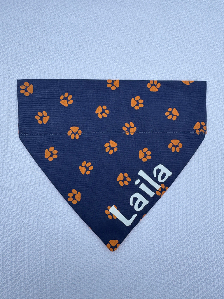 a navy dog bandanna with orange paw prints