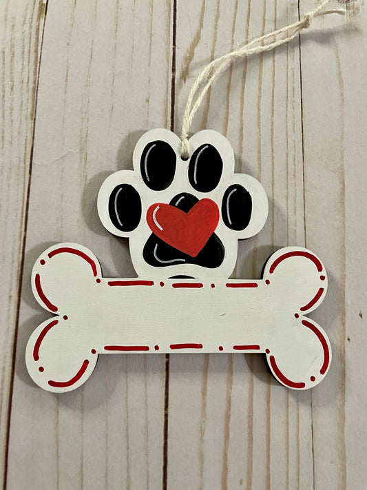 A wooden ornament with a paw print on top and a bone below rests on a wooden table